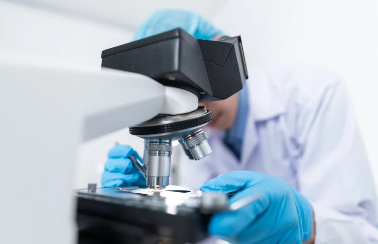 A biochemist researches medications in the laboratory using a microscope