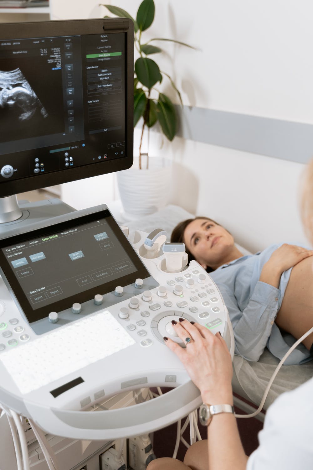 A hand reaches out to use an ultrasound machine, made in the Medtech industry, for a pregnant woman