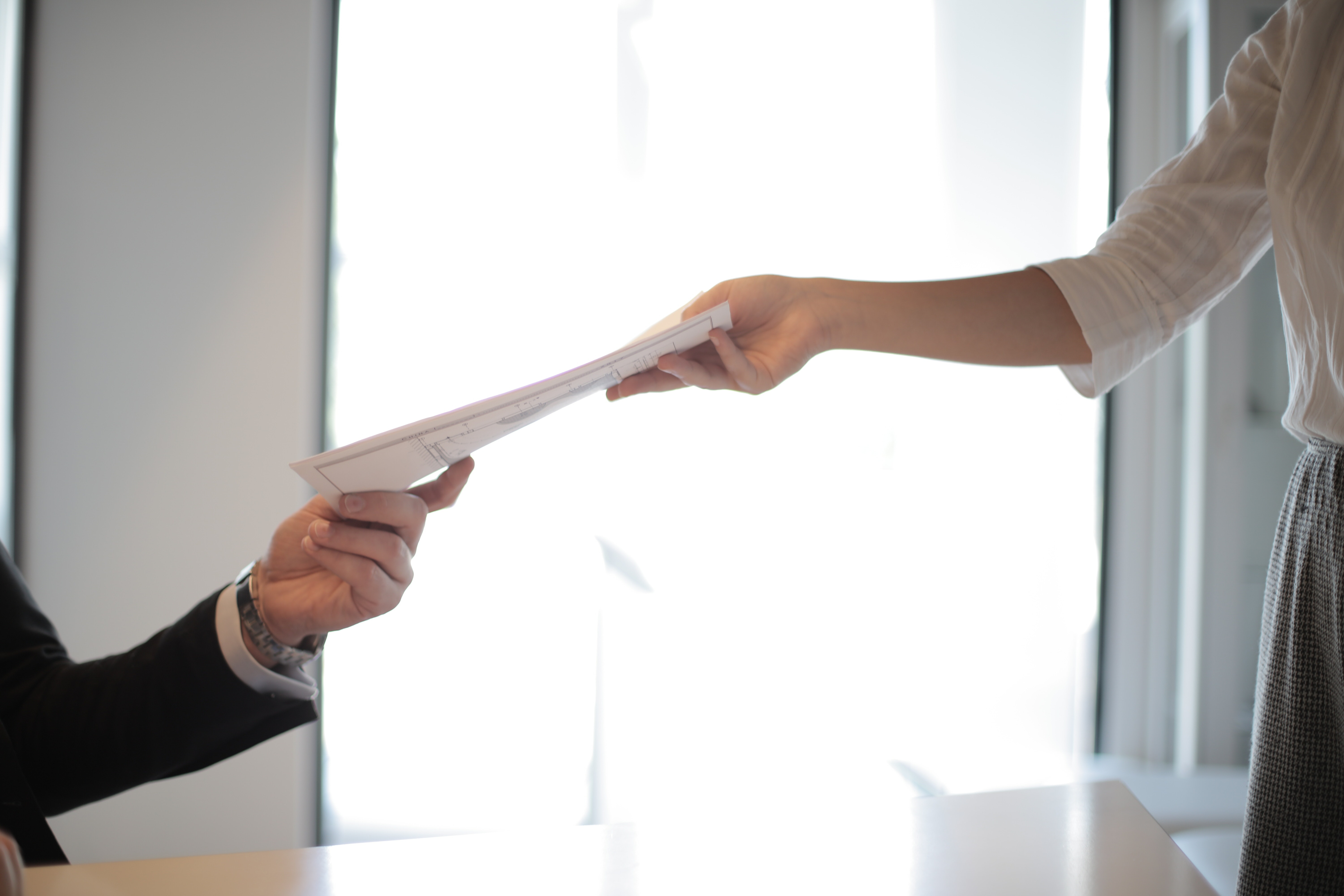 A job applicant hands her CV to a hiring manager during a MedTech job interview.