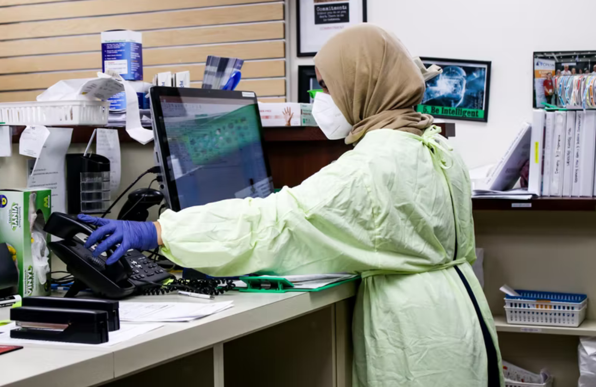 A woman working in the pharmaceutical industry works at a computer in a pharmacy setting