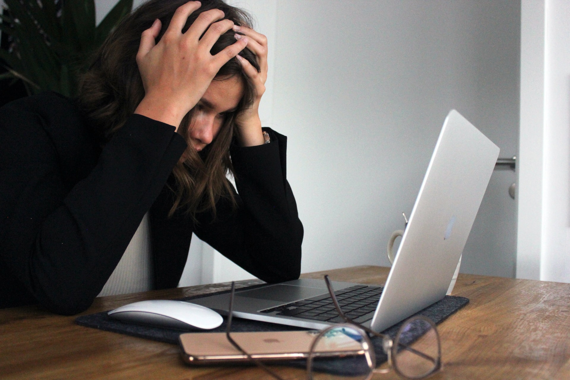 Woman sits at laptop with hands on her head while feeling frustrated from her career.